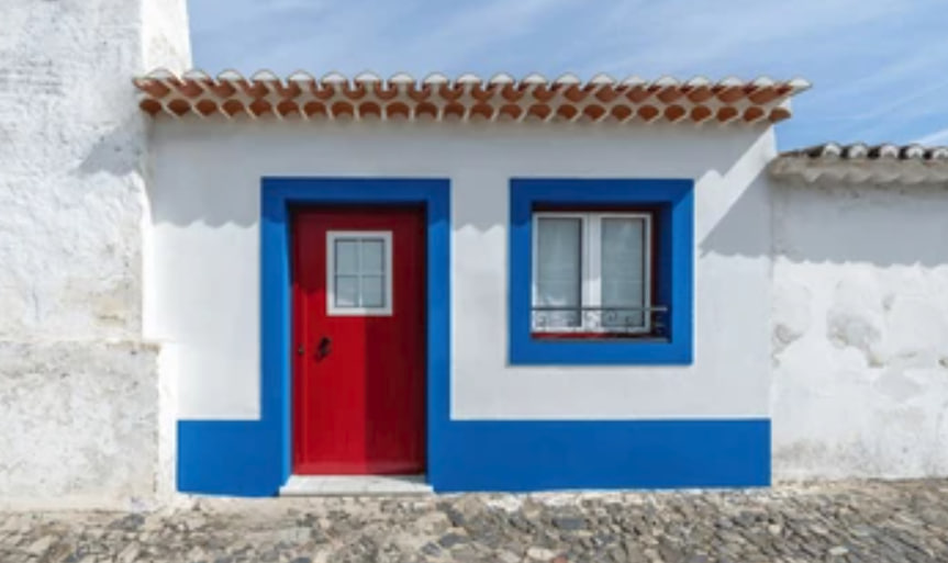 Casa encalada de zócalos y ventanas azules en el Algarve (Portugal).